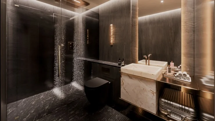 Modern bathroom with a glass shower, dark stone tiles, wall-mounted lighting, dual sink vanity with marble, and neatly arranged toiletries.