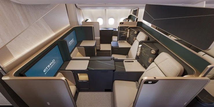 Interior view of an Etihad Airways business class cabin featuring sleek, modern seats with privacy dividers and large entertainment screens.