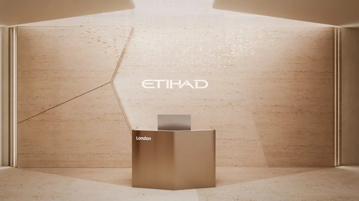 Modern reception area featuring a minimalist design with a beige stone backdrop and the Etihad logo illuminated above a sleek front desk labeled 'London'.