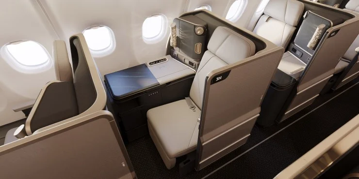 Interior view of a modern airplane business class cabin featuring an individual seat design, a large window, and a stylish table.