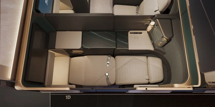 An aerial view of a luxurious airplane cabin, showcasing individual seating areas with beige upholstery, a sleek table surface, and modern lighting.