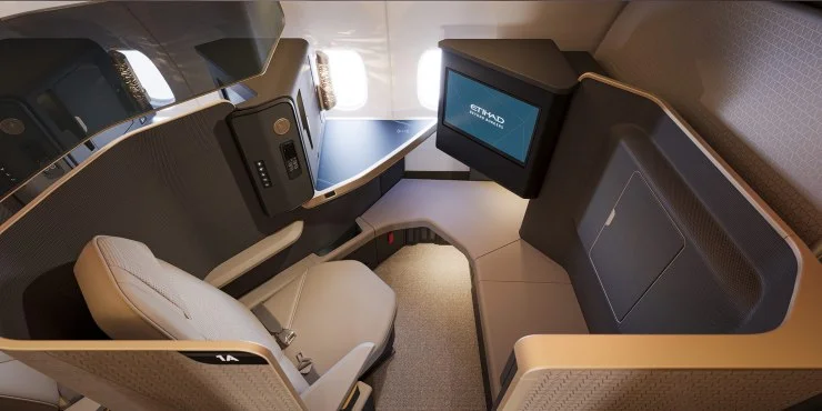 Interior view of a first-class airplane seat featuring a spacious layout, individual entertainment screen, and modern design elements.