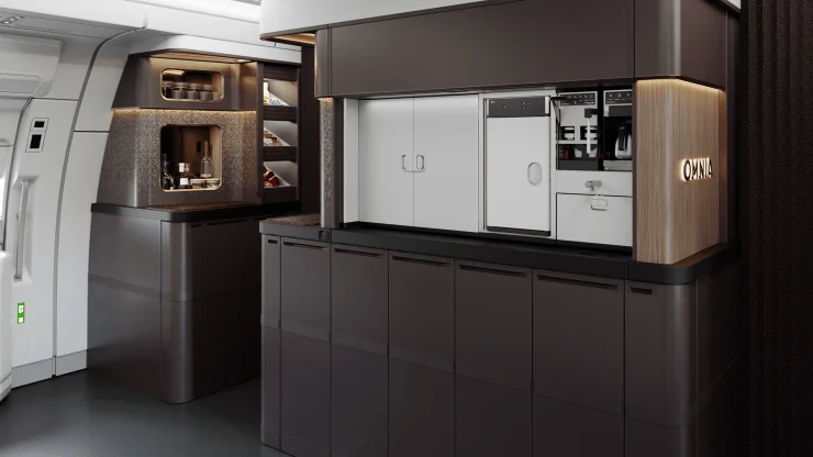 Interior view of an aircraft galley featuring a modern design, with dark cabinets, shelves displaying glassware, and a coffee machine.