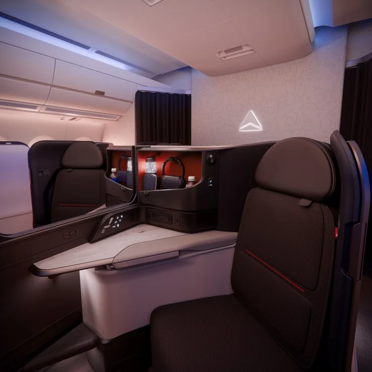 Interior view of a modern airplane seat in business class, featuring a sleek design, privacy partition, and ambient lighting.