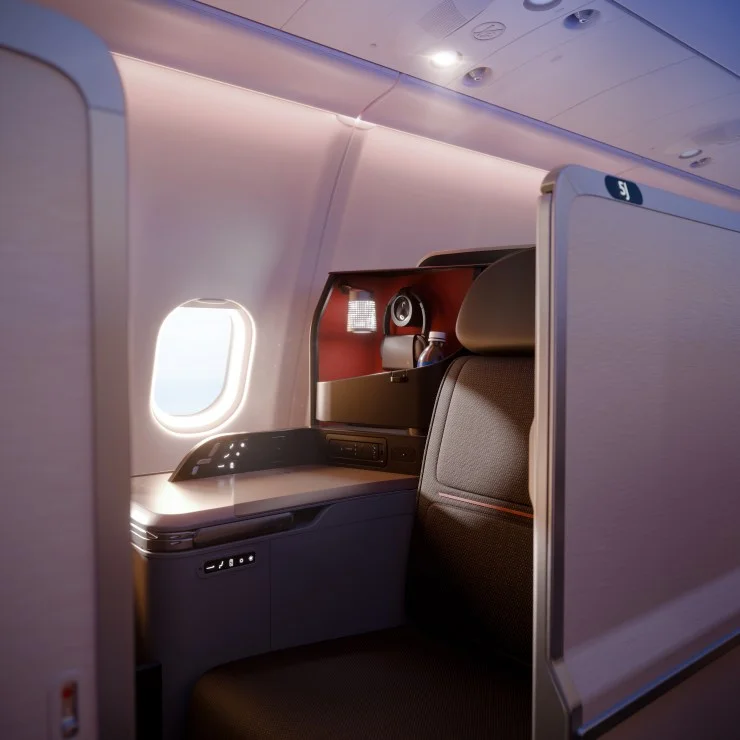 Interior view of a first-class airplane seat with a personal workspace, including a window, modern amenities, and soft lighting.