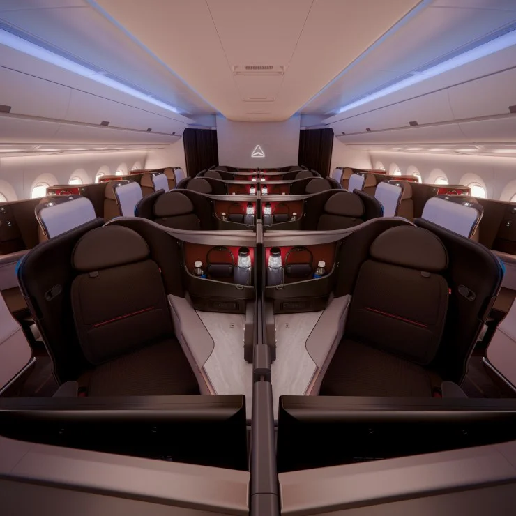 Interior view of a modern airplane cabin featuring spacious seating arrangements with privacy dividers and ambient lighting.