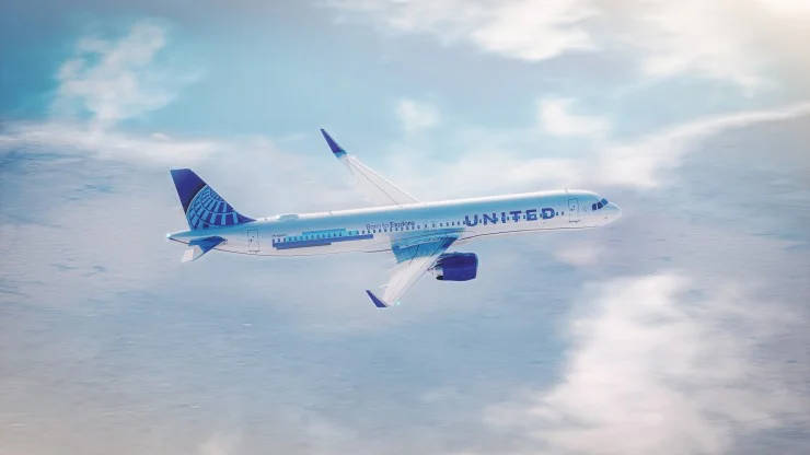 A United Airlines airplane flying above the clouds against a blue sky.