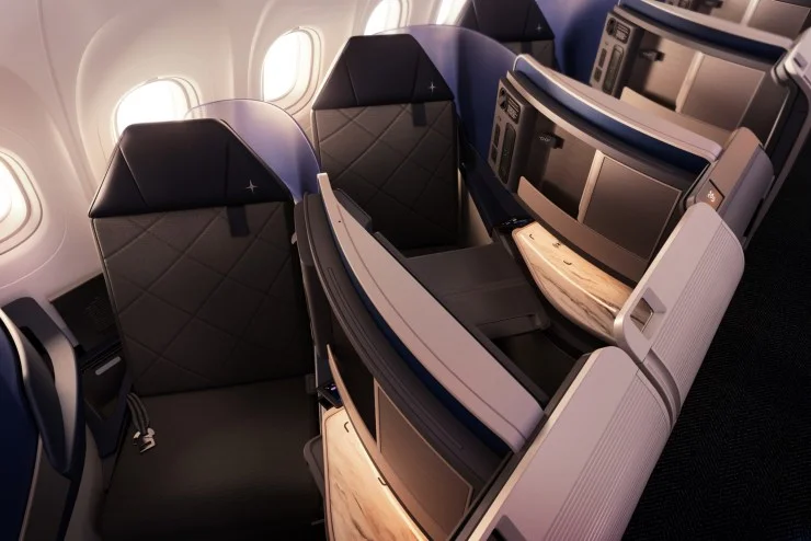 Interior view of an airplane featuring luxurious business class seating with spacious layouts and large windows.