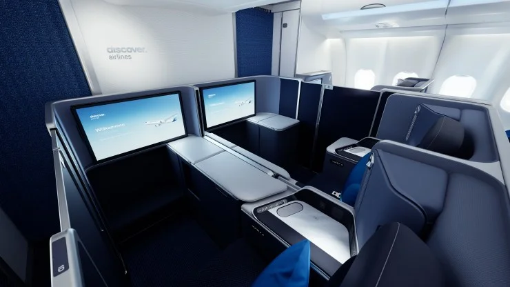 Interior view of a modern airline cabin featuring private seating areas, screens, and stylish design elements.