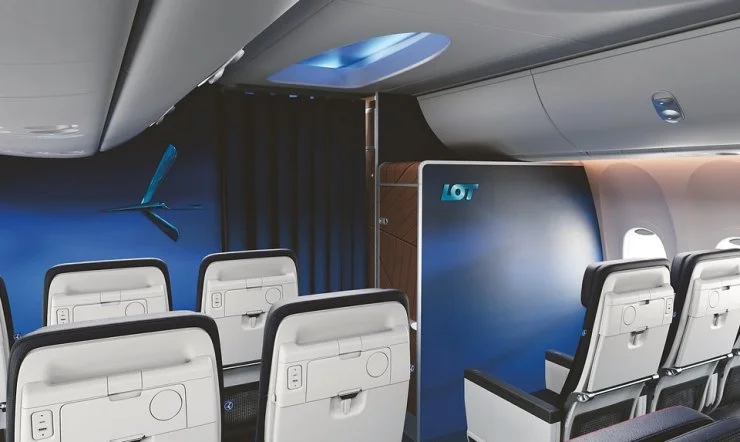 Interior view of an aircraft cabin featuring modern seating and a partition with LOT Polish Airlines branding.