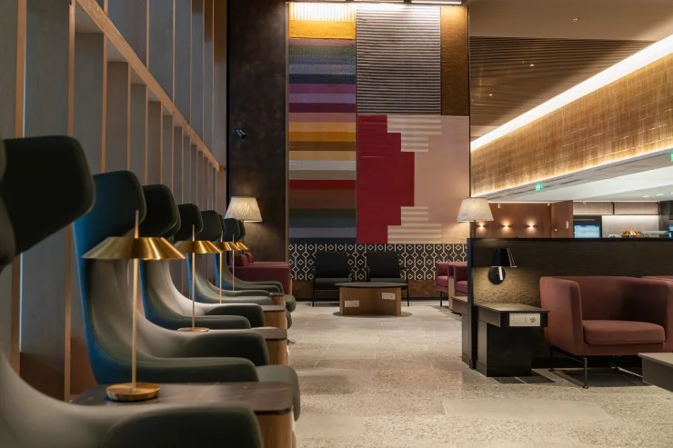 Interior view of the LATAM Lounge in Lima featuring modern seating, stylish lighting, and vibrant textured wall art that reflects South American aesthetics.