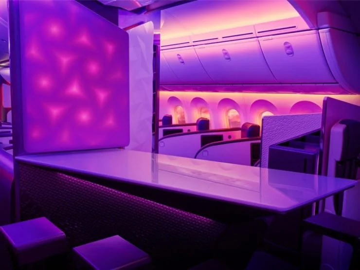 Interior view of a luxury aircraft cabin featuring a modern purple-lit bar area and seats in the background.