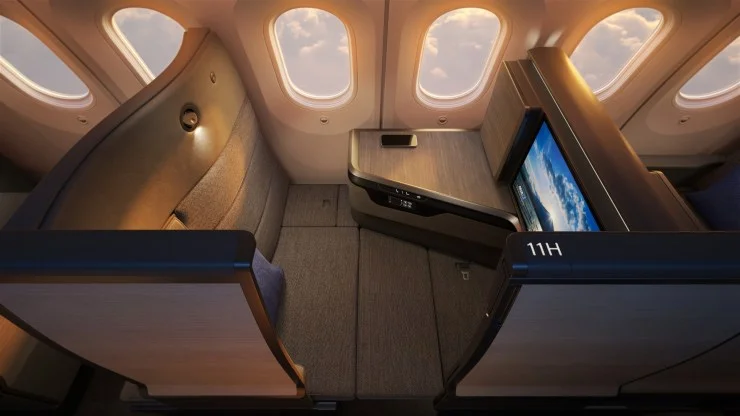 Interior view of ANA's THE Room FX business class seat featuring a spacious design with a large entertainment screen, side console, and warm lighting.
