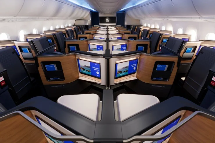 Interior view of United Airlines' Polaris business class cabin featuring individual seats with sliding privacy panels and large entertainment screens.