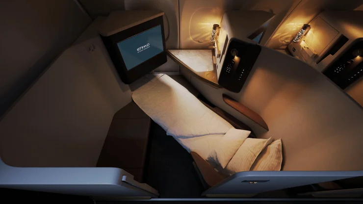 Interior view of Etihad Airways' new A321LR First Class suite, showcasing a private enclosed space with a lie-flat bed, large screen, and elegant design features.