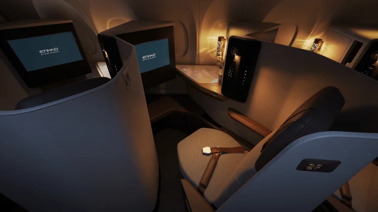 Interior view of Etihad's new A321LR First Class Suite, featuring a private enclosed space with a lie-flat bed, screens, and ambient lighting.