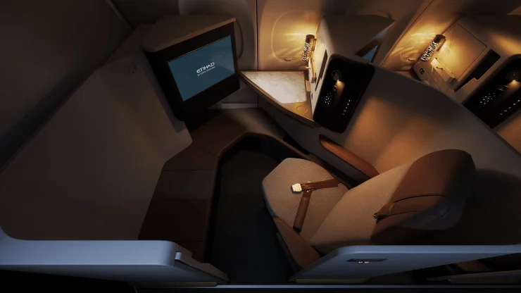 Interior view of Etihad's new narrowbody First Class Suite featuring a lie-flat bed, a large screen, and elegant design elements.