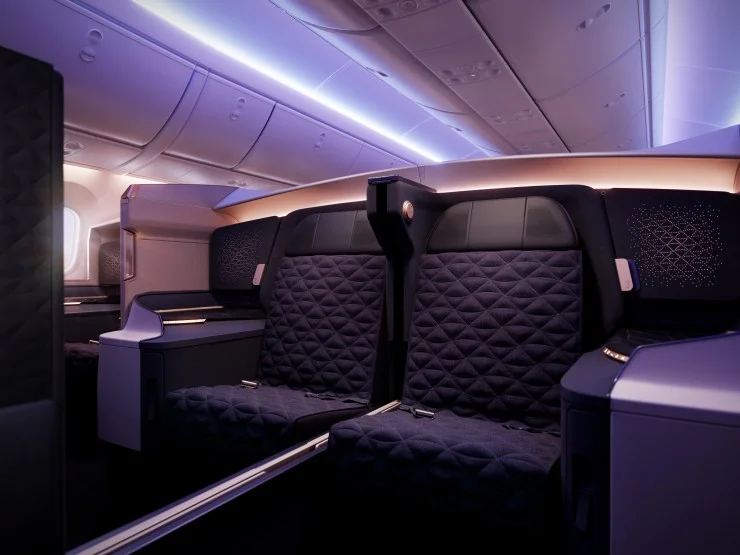 Interior view of Riyadh Air's Business Class cabin showcasing plush seating with modern design elements and soft purple ambient lighting.