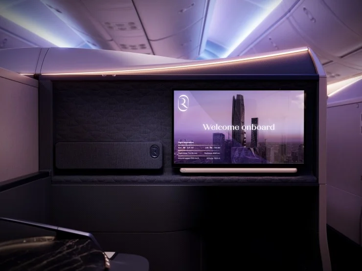 Close-up view of a luxurious airline cabin featuring a modern welcome screen with flight information and elegant design elements.
