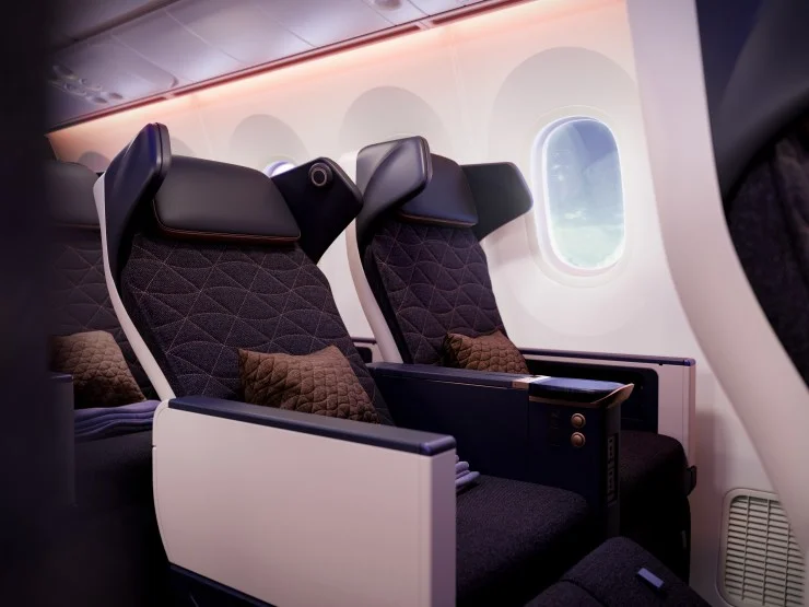 Interior view of Riyadh Air's Premium Economy seating featuring two seats with quilted upholstery, side armrests, and a window in the background.